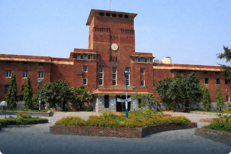 Red brick university campus building with a central clock tower and landscaped garden, representing Delhi University for DU MBA Admission 2026 CAT Score reference.